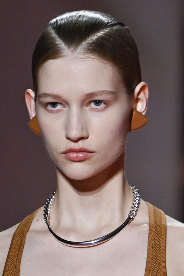 Nahaufnahme eines Models mit geometrischen Ohrringen und einer silbernen Halskette.