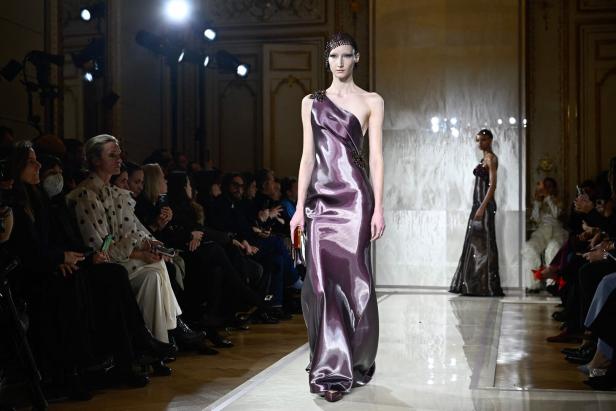 Eine Frau in einem violetten Kleid auf dem Laufsteg während einer Modenschau.