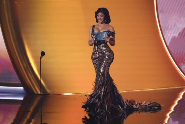 Cardi B steht auf einer Bühne und hält eine Karte in der Hand.