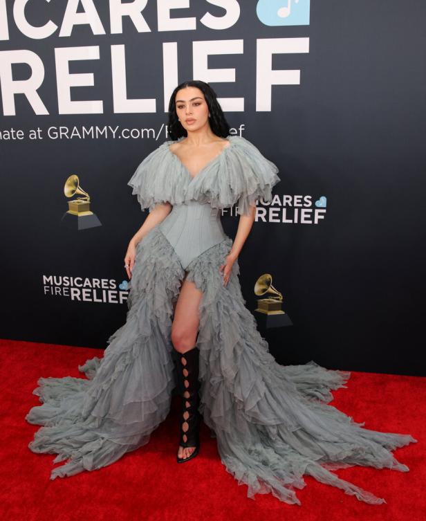 Charli XCX in einem grauen, gerafften Kleid auf dem roten Teppich.