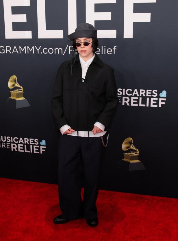Billie Eilish auf dem roten Teppich bei einer Veranstaltung von MusiCares in dunkler Kleidung und Hut.