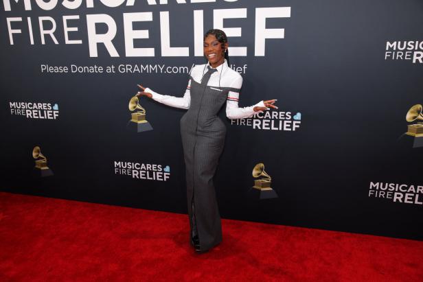 Eine Frau posiert auf dem roten Teppich vor einem „MusiCares Fire Relief“-Hintergrund.