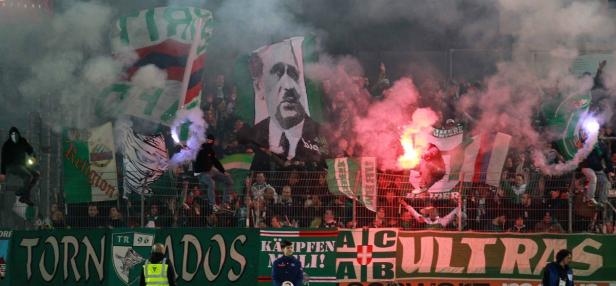 Fußballfans zünden Bengalos und schwenken Fahnen im Stadion.