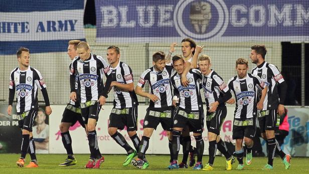 Eine Gruppe Fußballspieler von Sturm Graz steht auf dem Rasen.