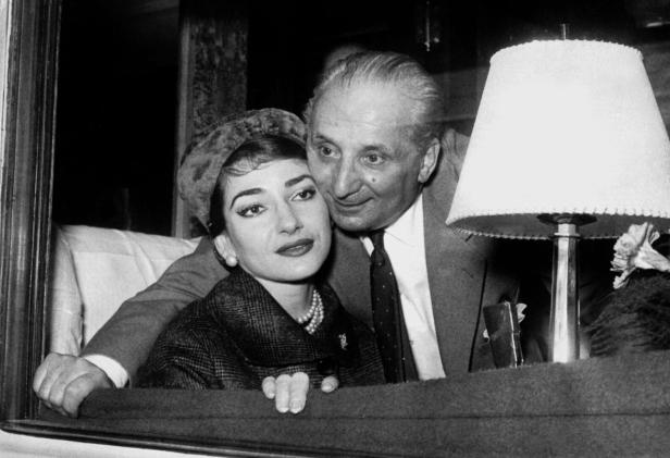 Maria Callas mit ihrem Ehemann Giovanni Battista Meneghini, umgeben von einer Lampe und einem Blumenstrauß.