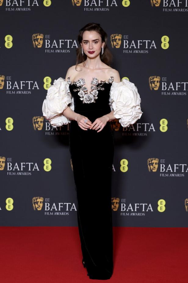 Lily Collins in einem schwarzen Kleid mit weißen Puffärmeln bei den BAFTA Film Awards.