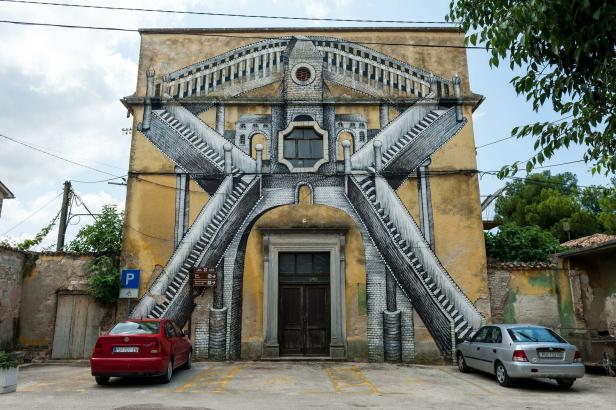 Ein Gebäude mit einer illusionistischen Treppenhausmalerei an der Fassade.