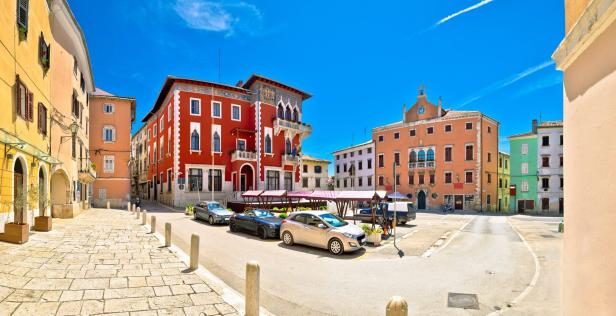Ein Platz mit bunten Gebäuden und geparkten Autos in Bale, Kroatien.