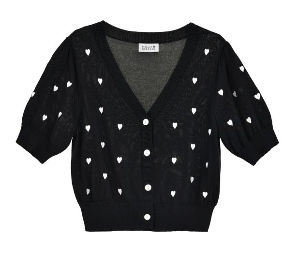 Eine schwarze Strickjacke mit weißen Herzen und weißen Knöpfen.