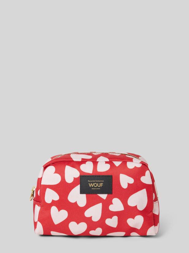 Eine rote Kosmetiktasche mit weißen Herzen und einem schwarzen Etikett der Marke Wouf.