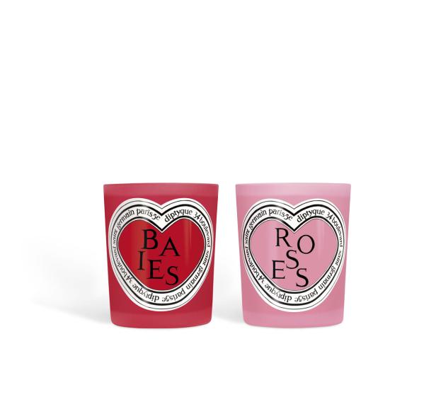 Zwei Duftkerzen von Diptyque, eine rote mit der Aufschrift „Baies“ und eine rosa mit der Aufschrift „Roses“.