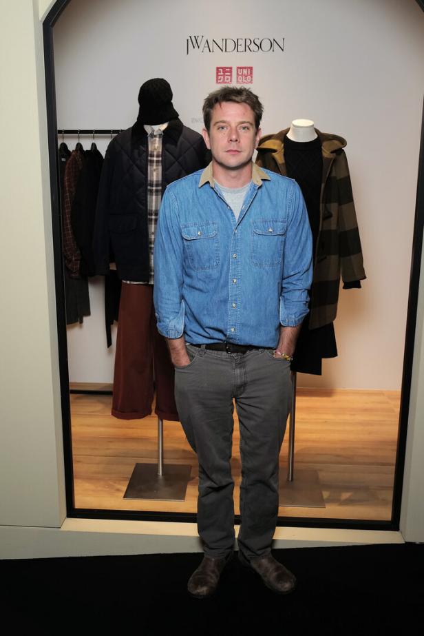 Ein Mann posiert vor einer J.W. Anderson und Uniqlo Kollektion.