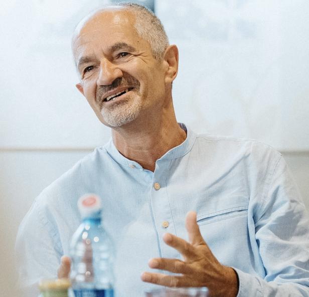 Ein Mann mit hellblauem Hemd gestikuliert während eines Gesprächs.