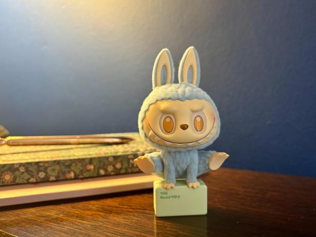 Eine blaue Monster-Spielfigur mit Hasenohren sitzt auf einem grünen Sockel.
