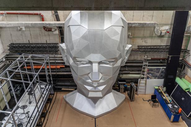 Ein riesiger, silberner Kopf im Stil einer geometrischen Skulptur, möglicherweise Falco.