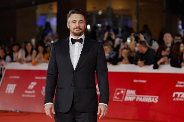 James Franco posiert auf dem roten Teppich in einem schwarzen Anzug.