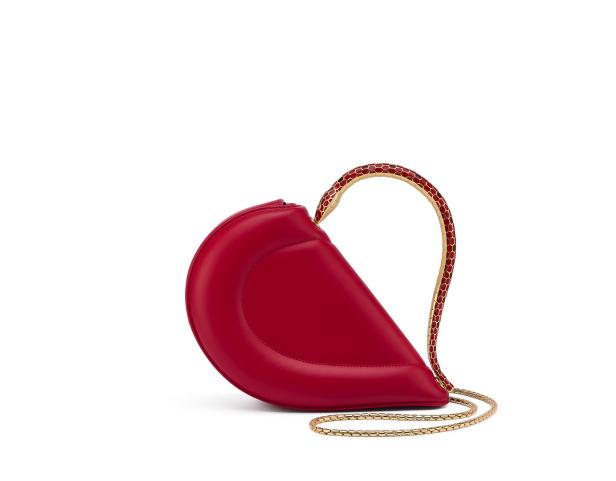Eine rote, halbmondförmige Handtasche mit goldenen Kettenriemen steht auf einem weißen Hintergrund.