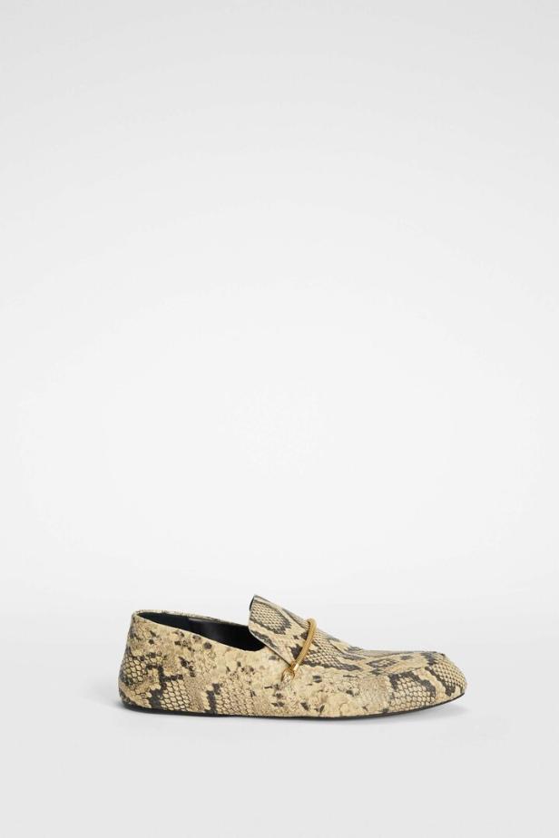 Ein Loafer mit Schlangenmuster und goldfarbener Zierspange auf einem weißen Hintergrund.