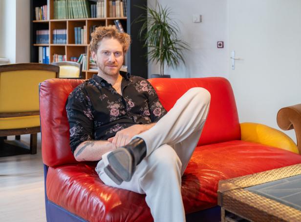 Lucas Fendrich sitzt auf einem roten Sofa.