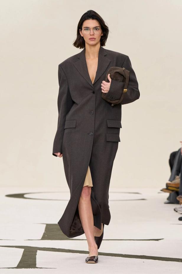 Kendall Jenner trägt einen übergroßen grauen Mantel und eine braune Handtasche auf dem Laufsteg.
