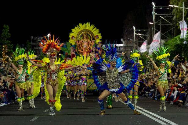 Eine Gruppe von Menschen in farbenfrohen Kostümen nimmt an einer Karnevalsparade teil.