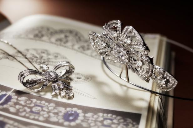 Eine Diamantbrosche und ein Diadem liegen auf einem aufgeschlagenen Buch.