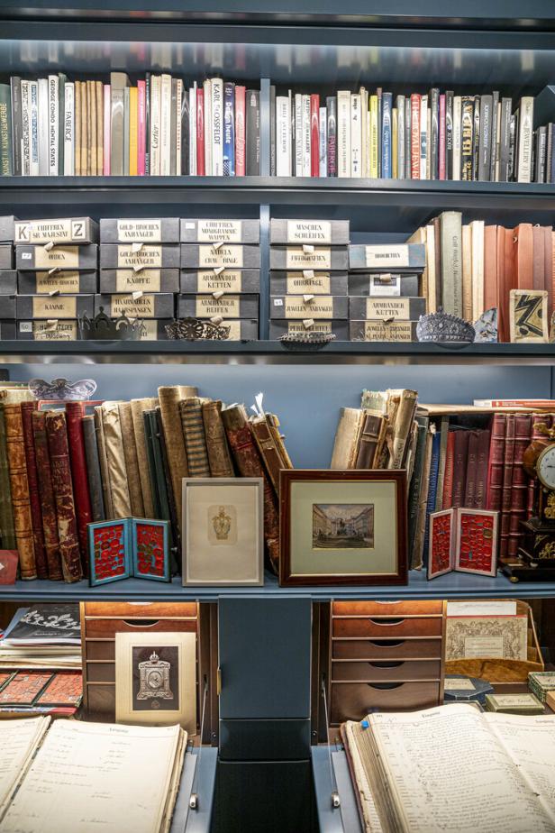 Ein Bücherregal mit Büchern, Schachteln mit Schmuck und gerahmten Bildern.