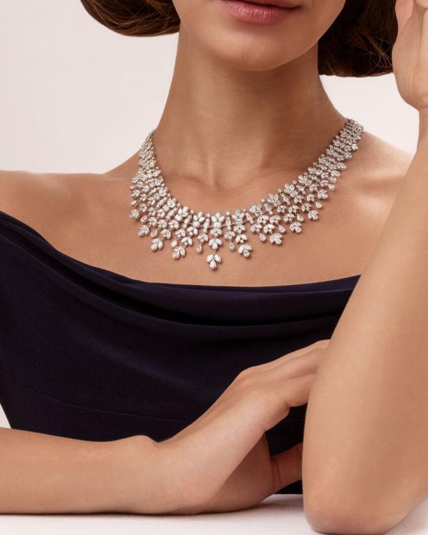 Eine Frau trägt eine auffällige Diamantkette zu einem dunkelblauen Kleid.