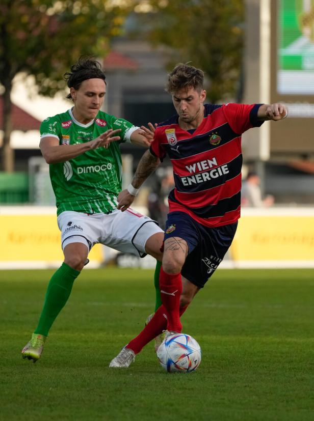 Zwei Fußballspieler kämpfen um den Ball auf dem Spielfeld.
