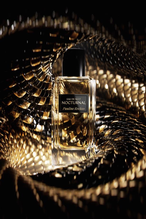 Eine Flasche „Eau de Nuit Nocturnal“ von Pauline Rochas vor einem goldenen Hintergrund.