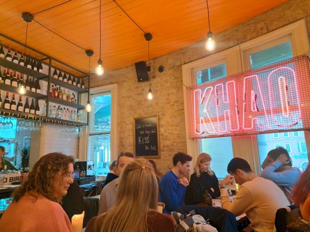 Gäste sitzen im Restaurant „Khao“ unter einer Neonreklame.