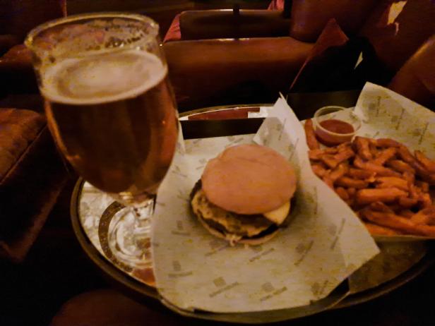 Ein Burger, Süßkartoffel-Pommes und ein Glas Bier auf einem Tablett.