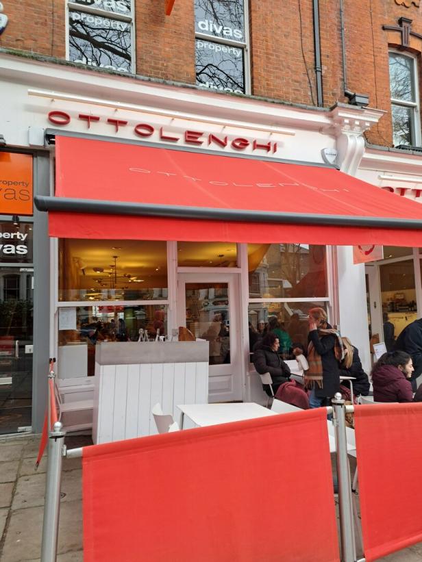 Das Restaurant Ottolenghi mit roter Markise und Gästen im Außenbereich.