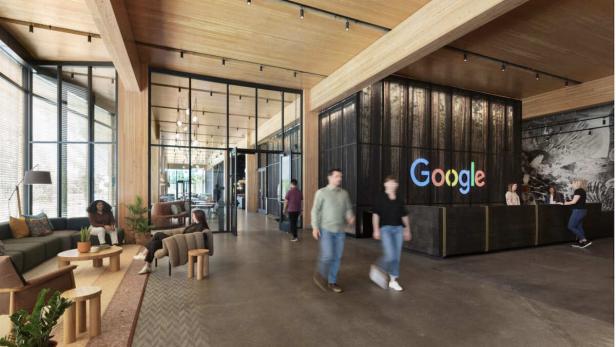 Die Lobby eines Google-Büros mit Menschen und dem Google-Logo hinter dem Empfangstresen.