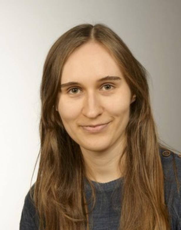 Porträt einer jungen Frau mit langen, glatten, braunen Haaren.