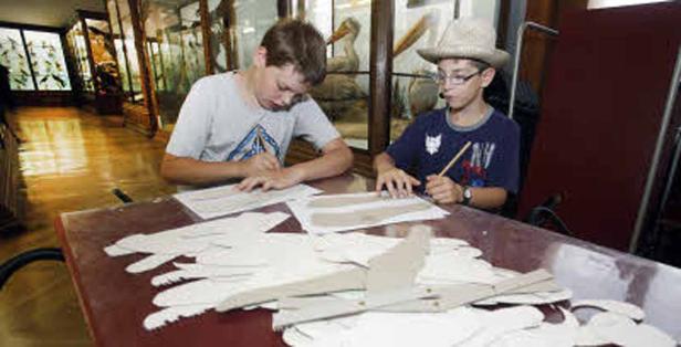 Zwei Jungen sitzen an einem Tisch und basteln Vogelmodelle.
