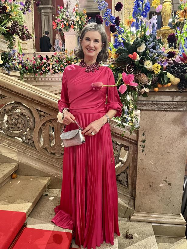 Eine Frau in einem pinkfarbenen Kleid steht auf einer Treppe mit Blumenschmuck.