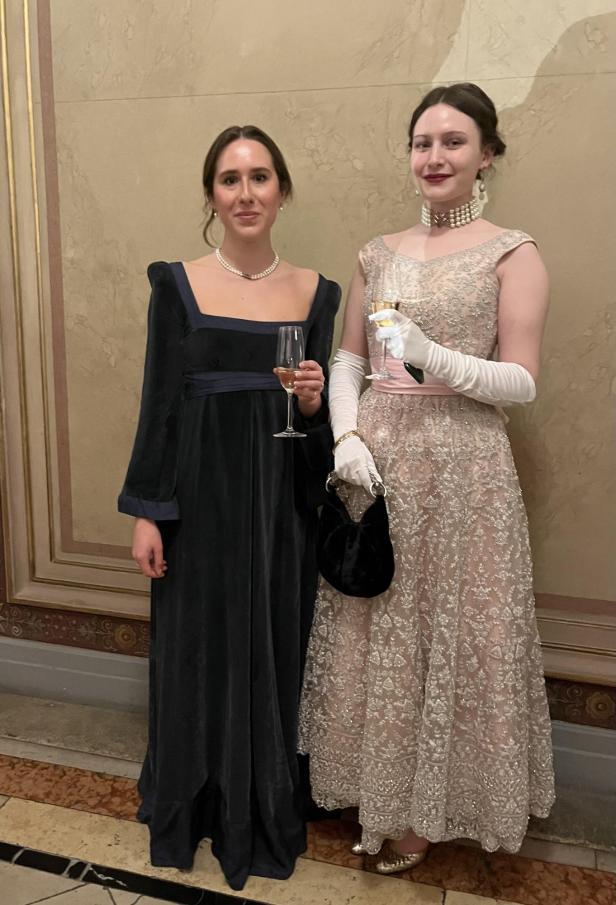 Zwei Frauen in Abendkleidern halten Champagnergläser.