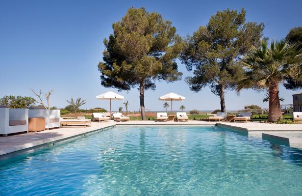 Ein Schwimmbad mit Liegestühlen und Sonnenschirmen an einem sonnigen Tag.