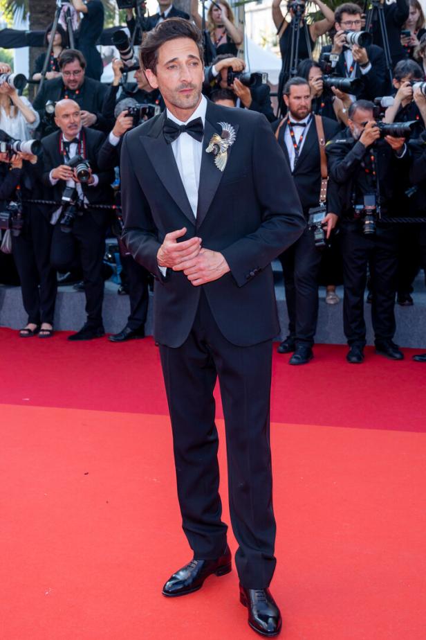 Adrien Brody posiert auf einem roten Teppich vor einer Gruppe von Fotografen.
