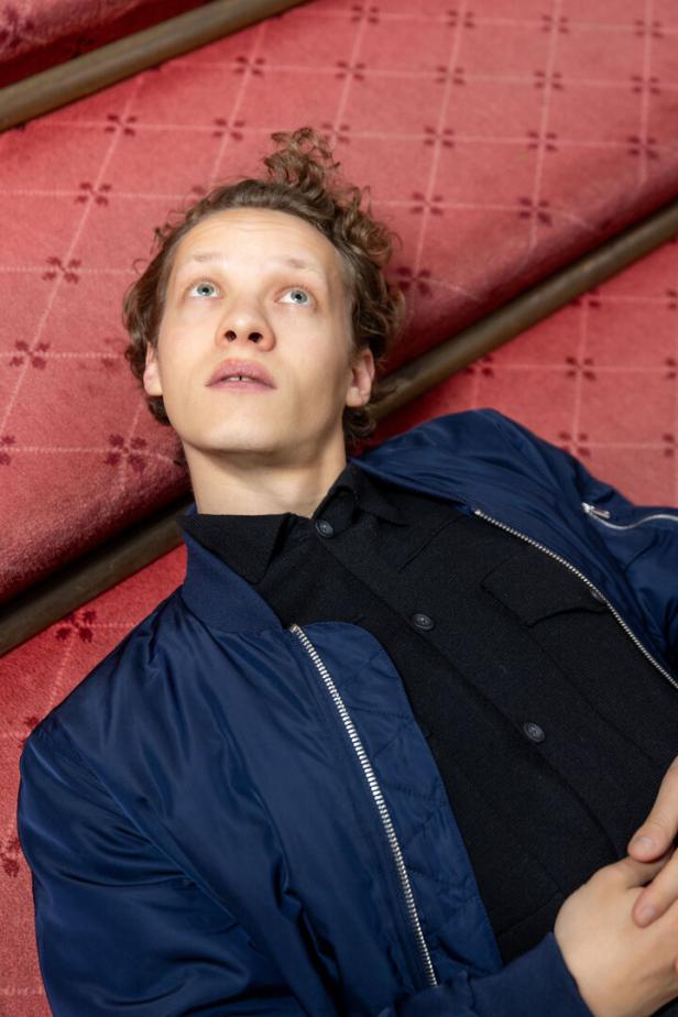 Ein junger Mann liegt auf einer roten Treppe und schaut nach oben.