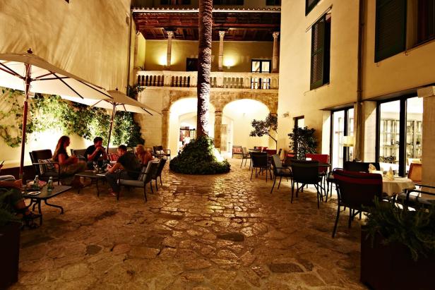 Ein Innenhof mit Gästen an Tischen bei Nacht.