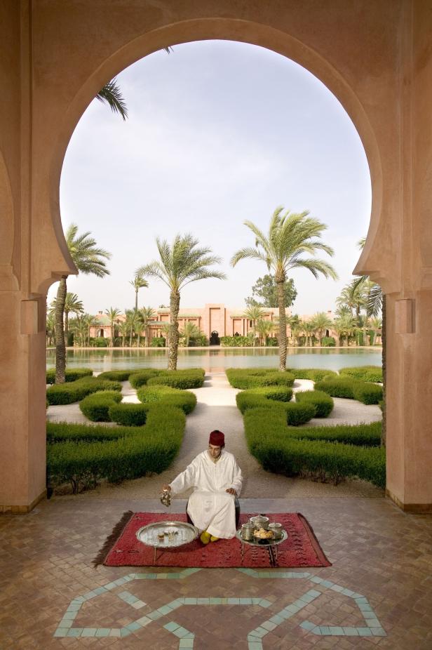 Ein Mann in traditioneller Kleidung gießt Tee in einem Garten in Marrakesch.