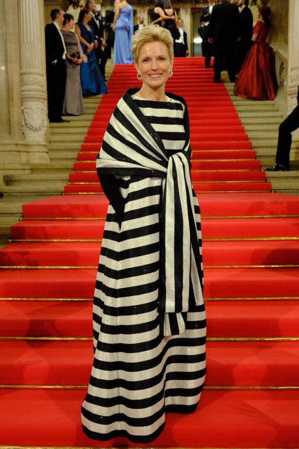 Eine Frau in einem gestreiften Kleid steht auf einer roten Treppe.