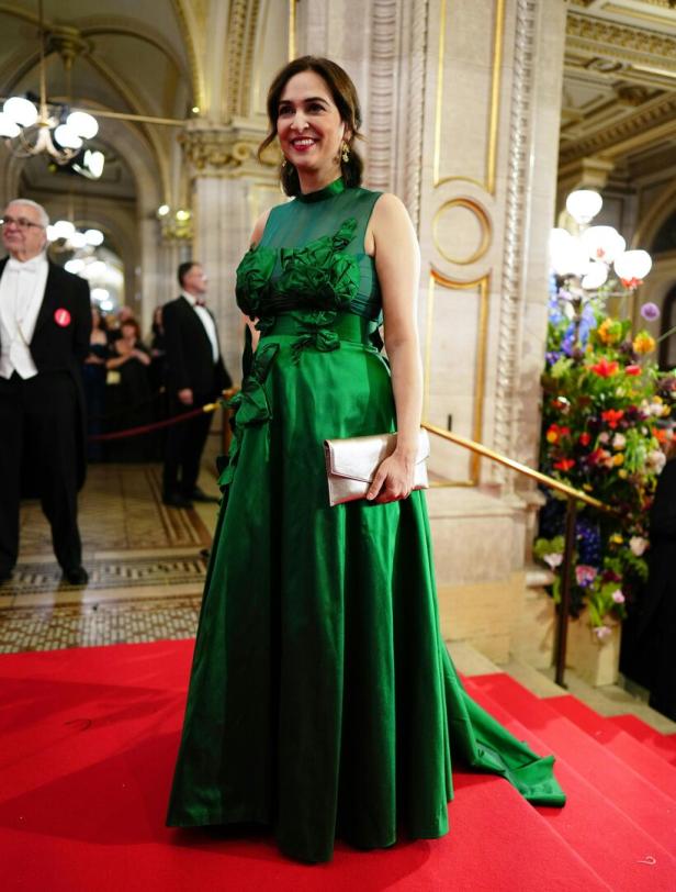 Eine Frau in einem grünen Kleid auf einer roten Treppe, möglicherweise bei einer Veranstaltung in der Wiener Staatsoper.