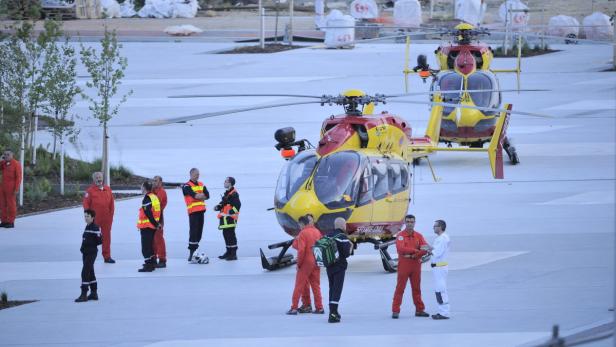 Zwei gelb-rote Hubschrauber stehen auf einem Flugfeld, umgeben von Einsatzkräften.