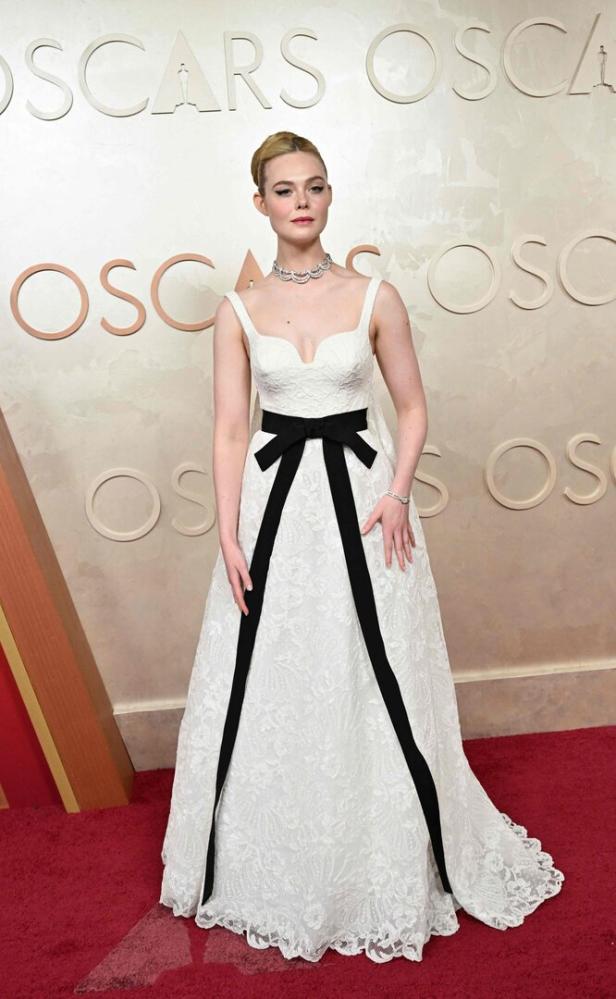 Elle Fanning in einem weißen Kleid mit schwarzer Schleife bei den Oscars.