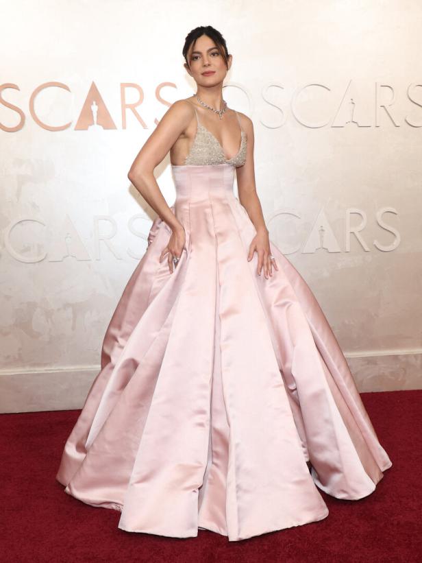 Eine Frau in einem rosa Ballkleid posiert auf dem roten Teppich der Oscars.