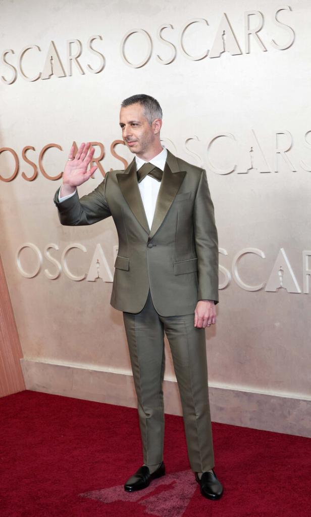 Jeremy Strong auf dem roten Teppich der Oscars, winkend.