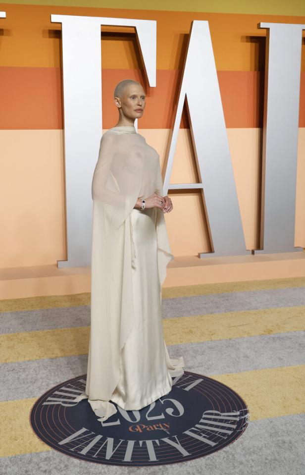 Eine Frau mit rasiertem Kopf in einem langen, hellen Kleid auf dem roten Teppich der Vanity Fair Oscar Party 2023.